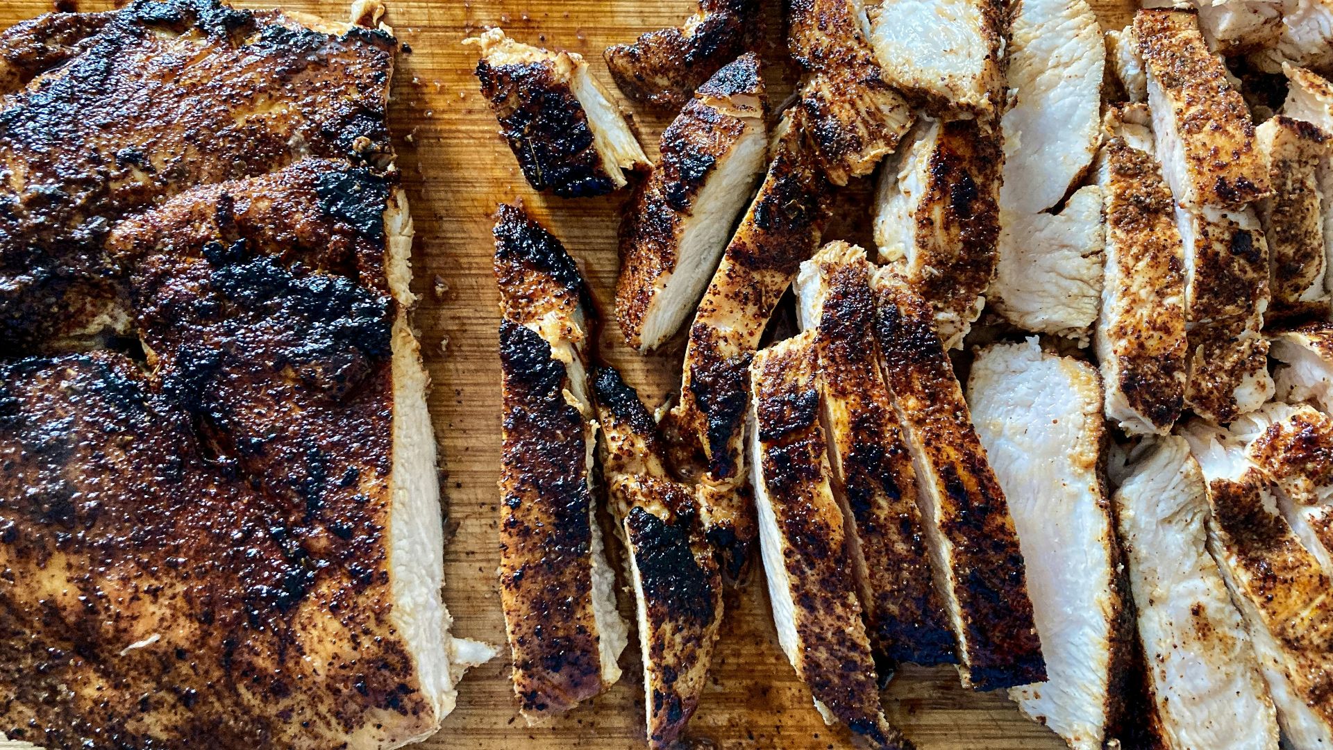 a wooden cutting board topped with sliced up meat