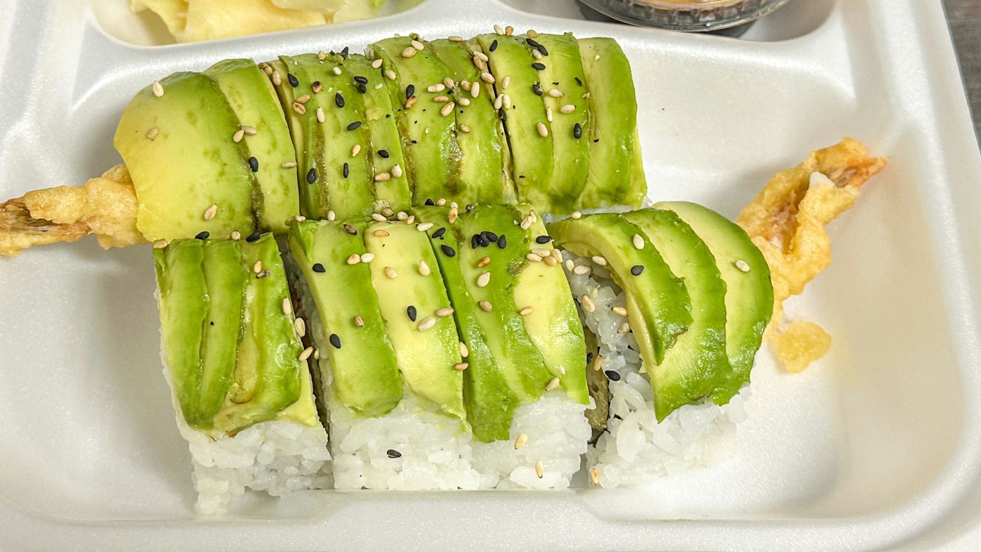 a plastic container filled with sushi and vegetables