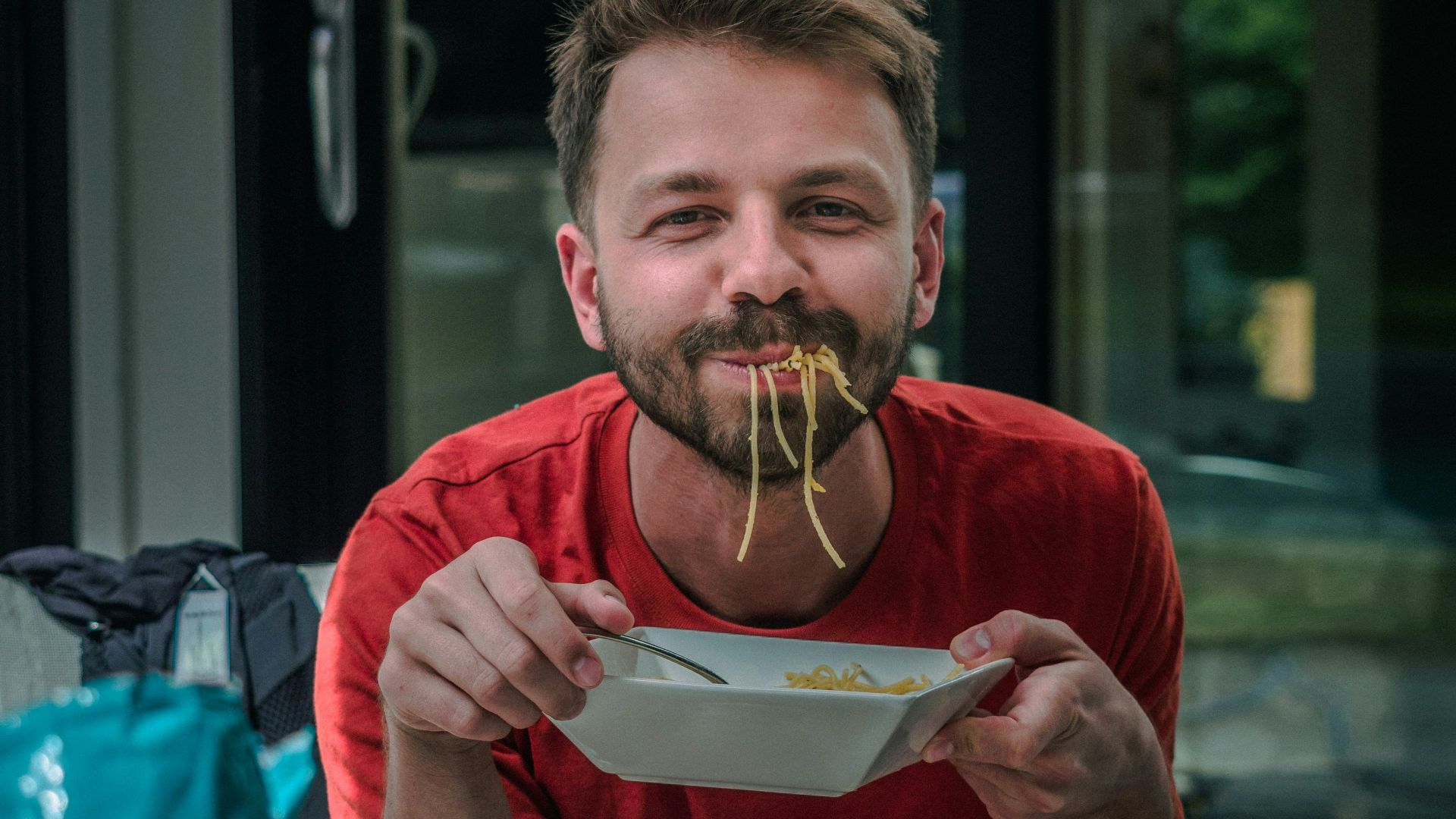 man in red crew neck t-shirt holding white and red labeled can