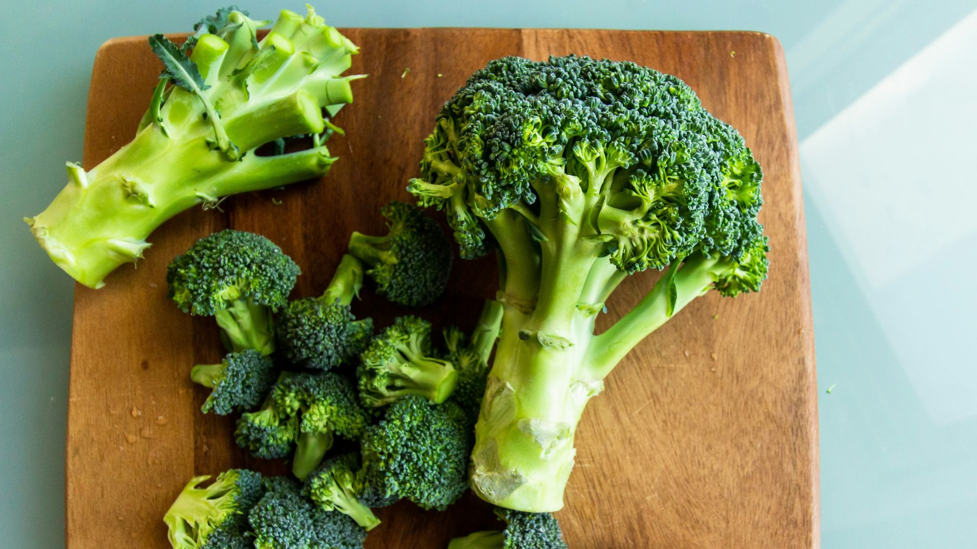 broccoli on brown wooden chopping board