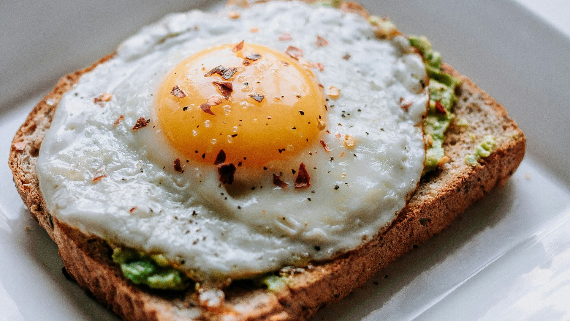 bread with sunny side-up egg served on white ceramic plate