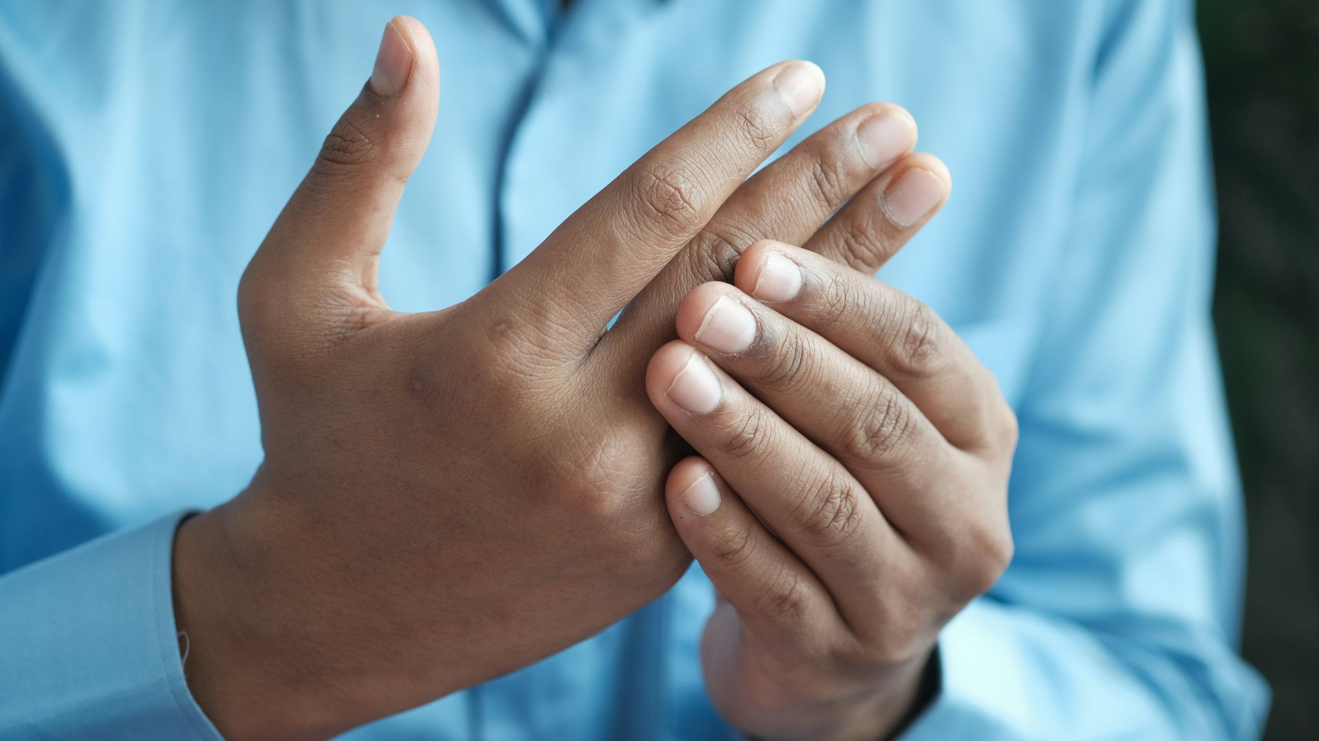 person in blue shirt showing left hand