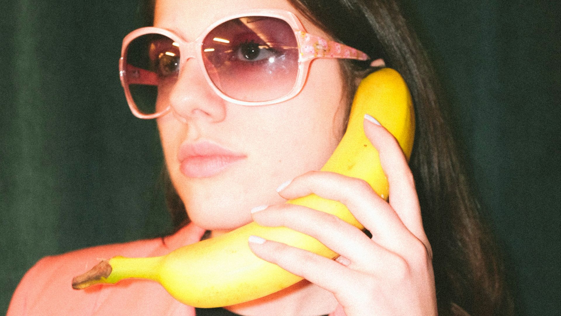 woman in pink blazer holding yellow banana