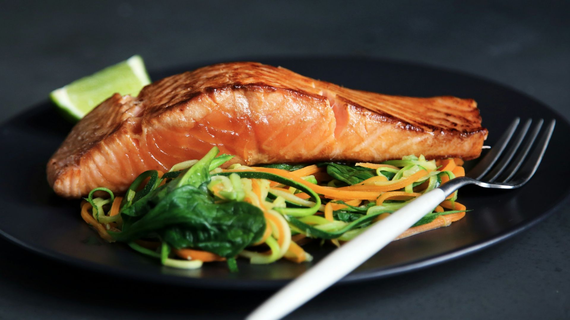 grilled fish, cooked vegetables, and fork on plate