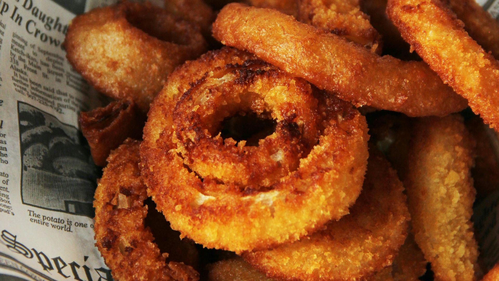 a pile of fried onion rings sitting on top of a newspaper