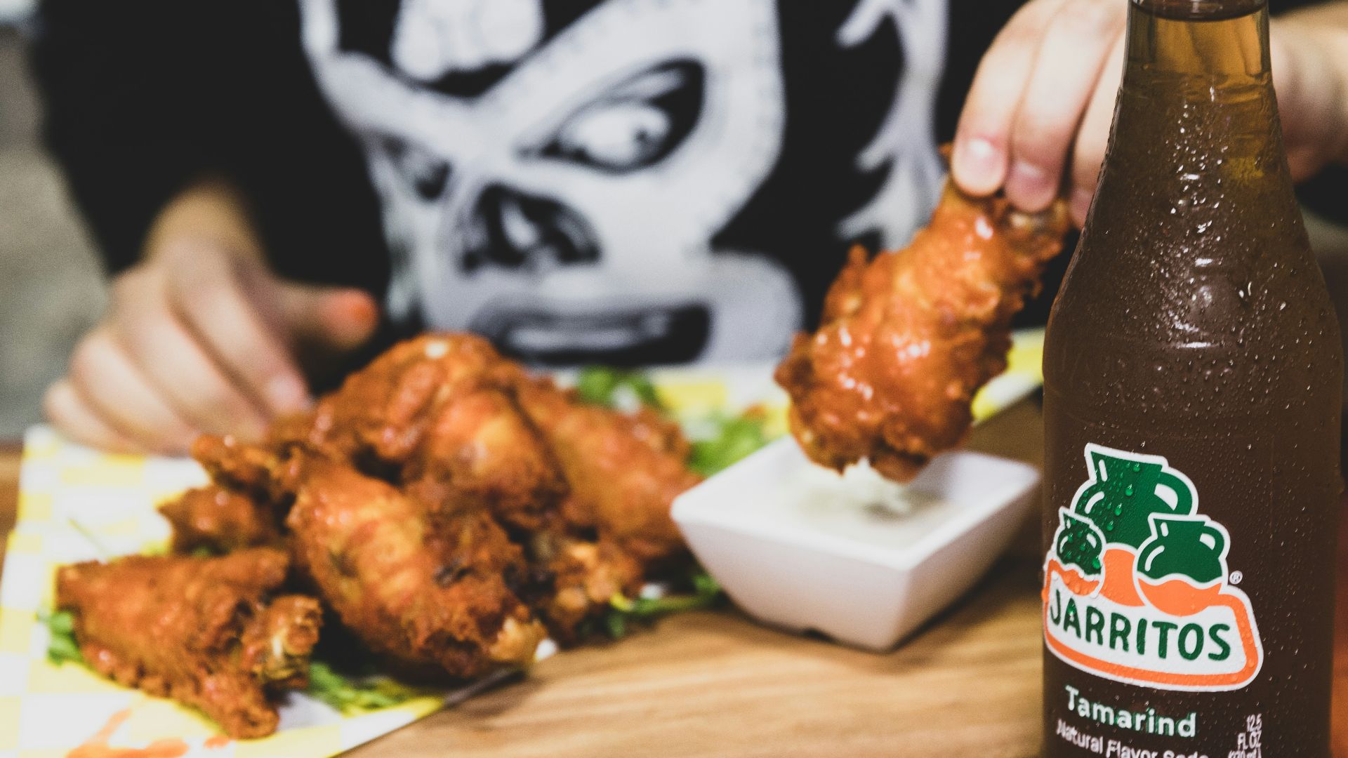 a person holding a bottle of beer over a plate of food