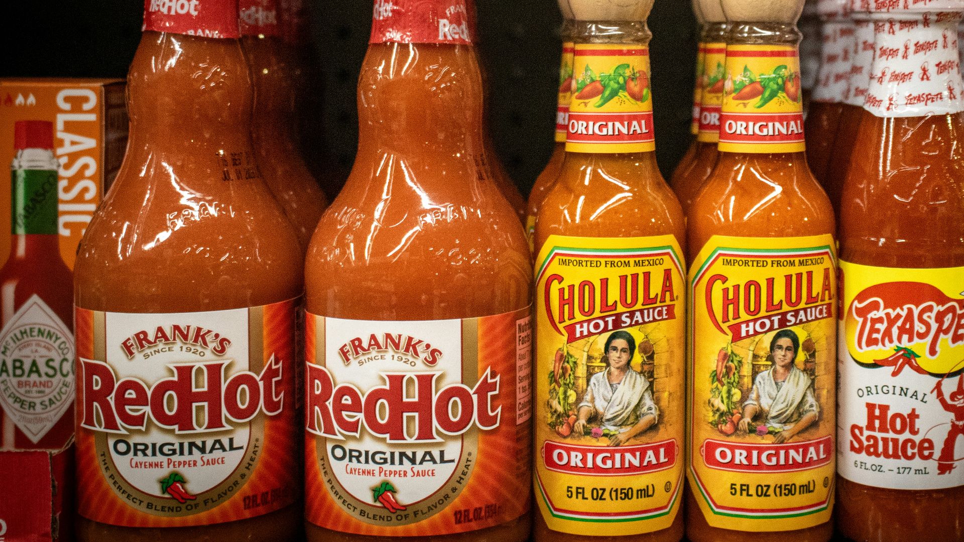 Hot sauce bottles line a store shelf.