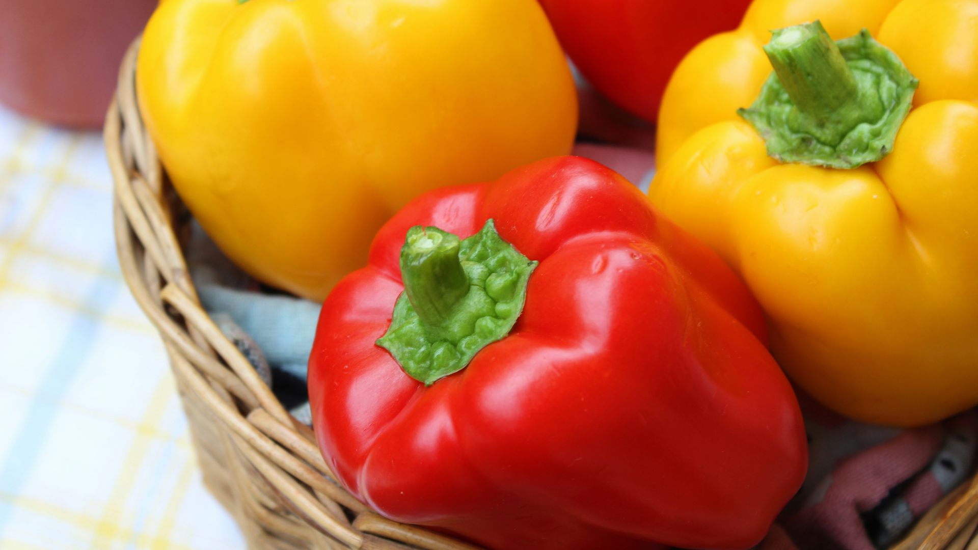 red and yellow bell peppers in brown woven basket