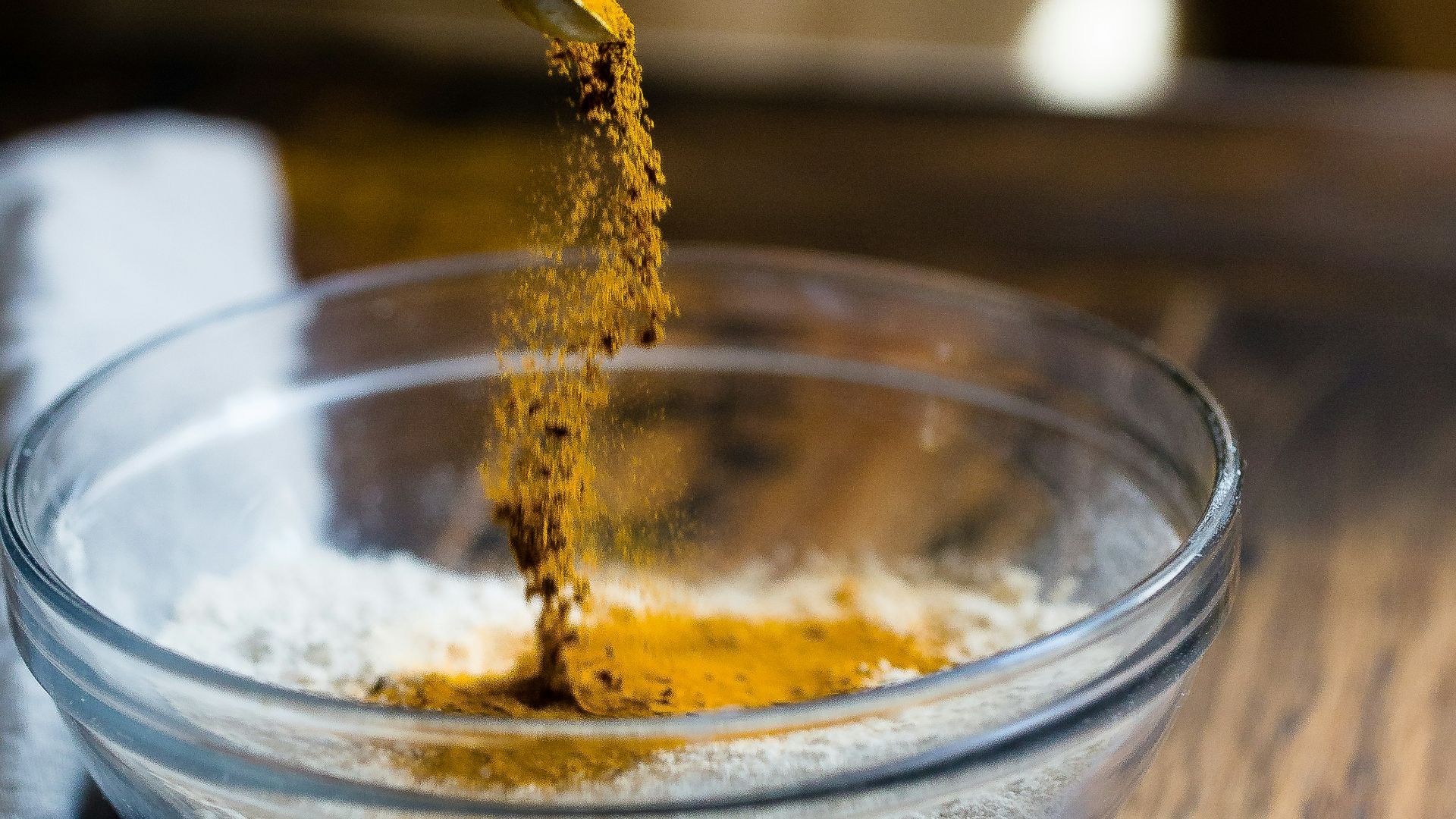 person pouring seasonings on clear glass bowl