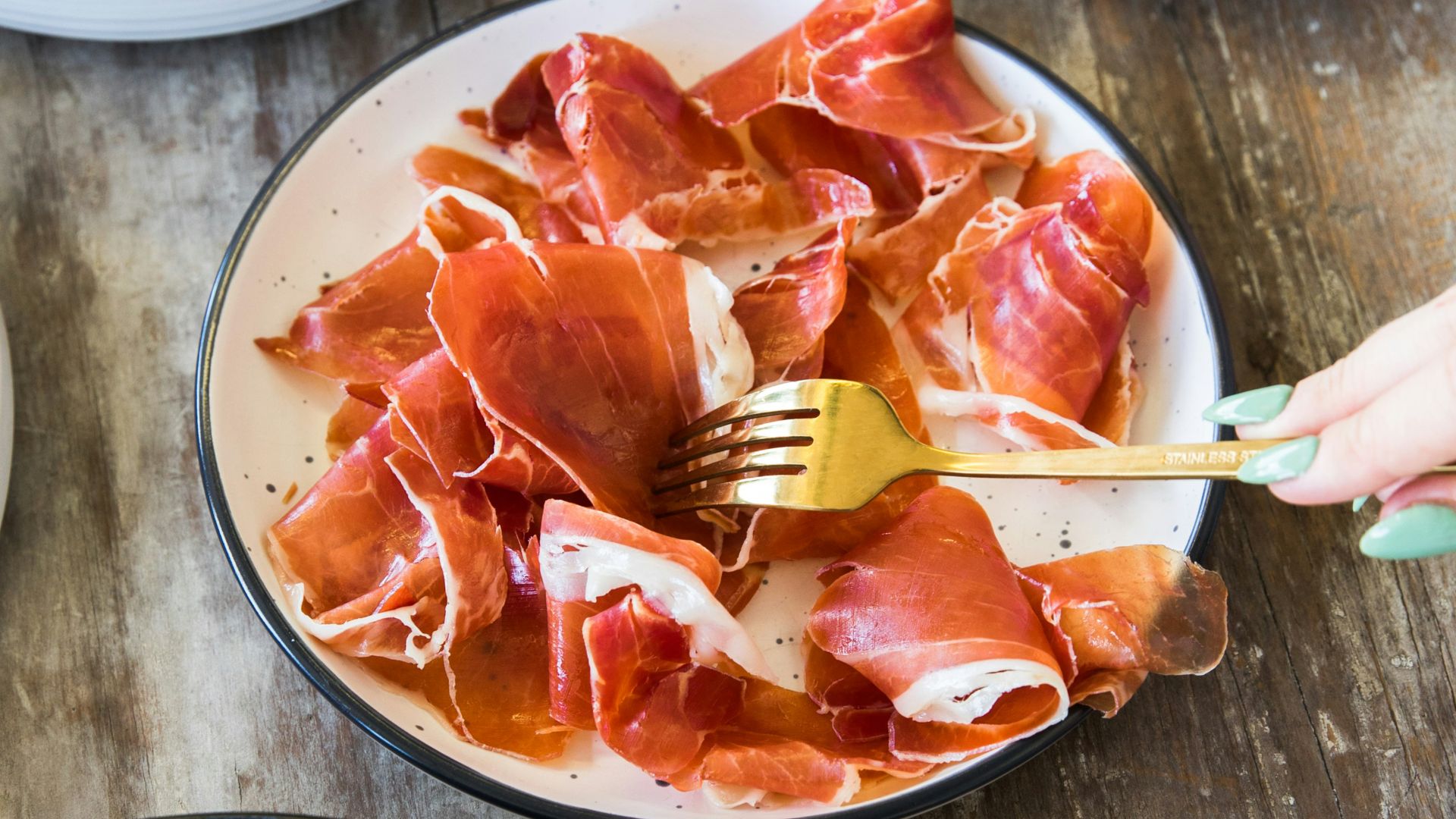 person holding chopsticks slicing meat on white ceramic plate