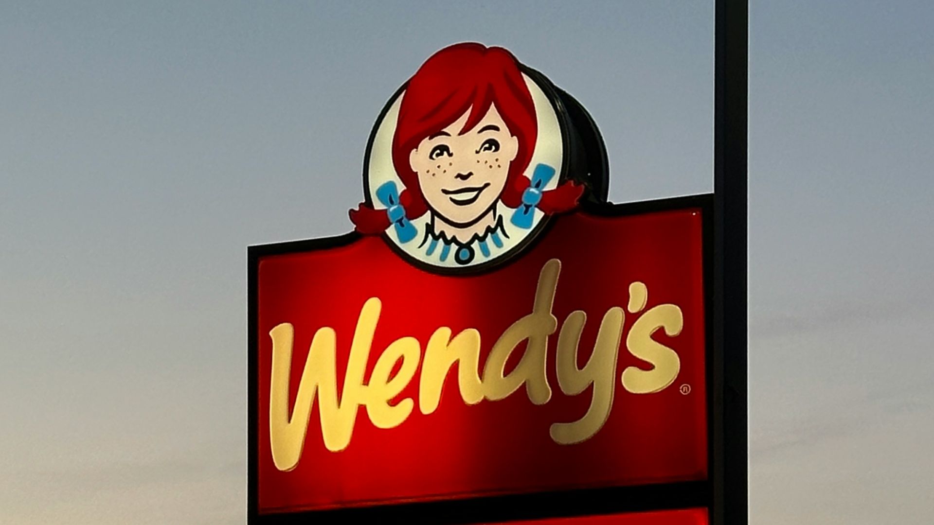 a sign for wendy's restaurant in a parking lot