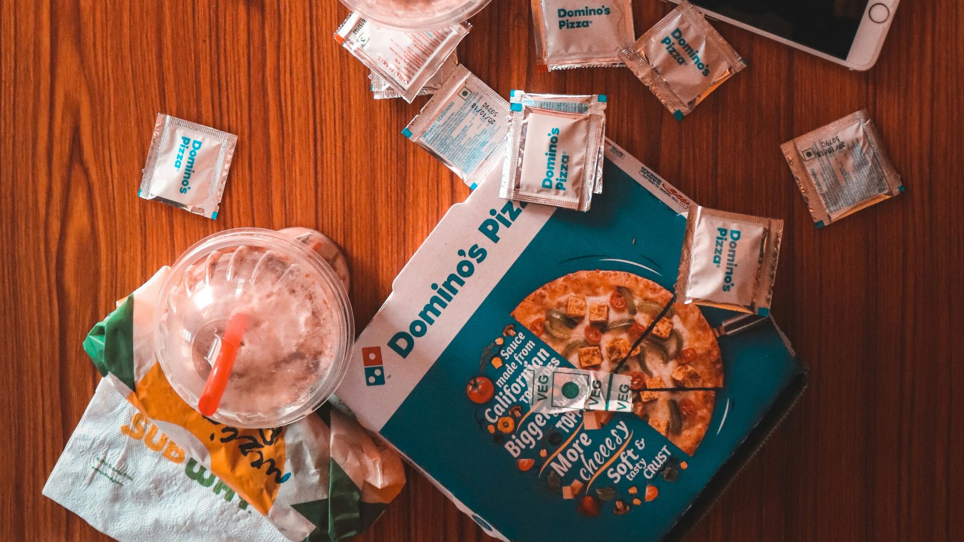 pizza and sauce packs beside iPhone on table