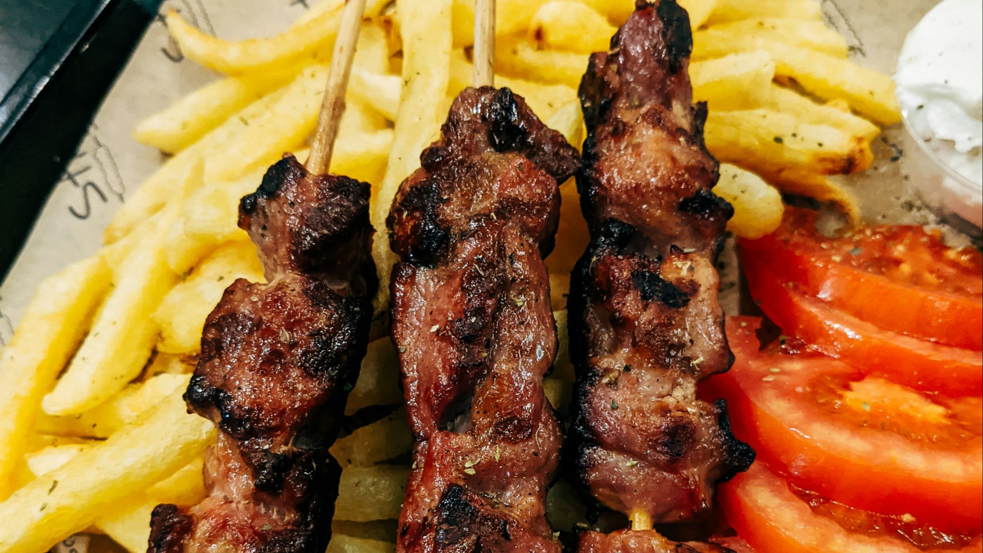 grilled meat with sliced tomato and green vegetable on white ceramic plate