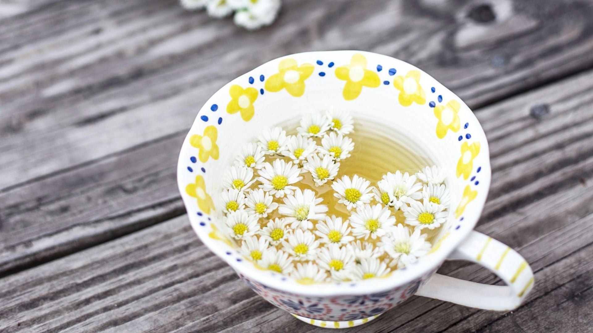 white and yellow cup with flowers on table