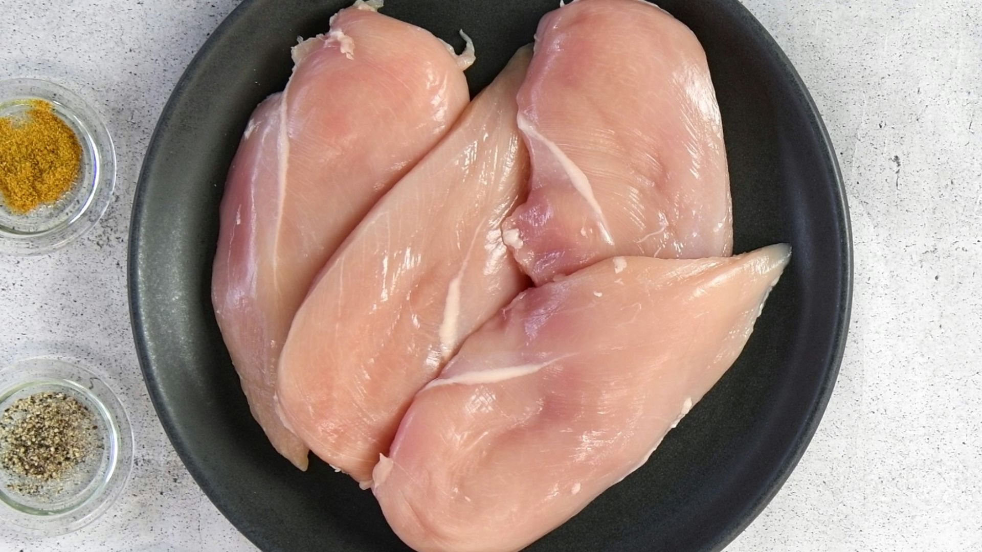 two raw chicken breasts in a black bowl