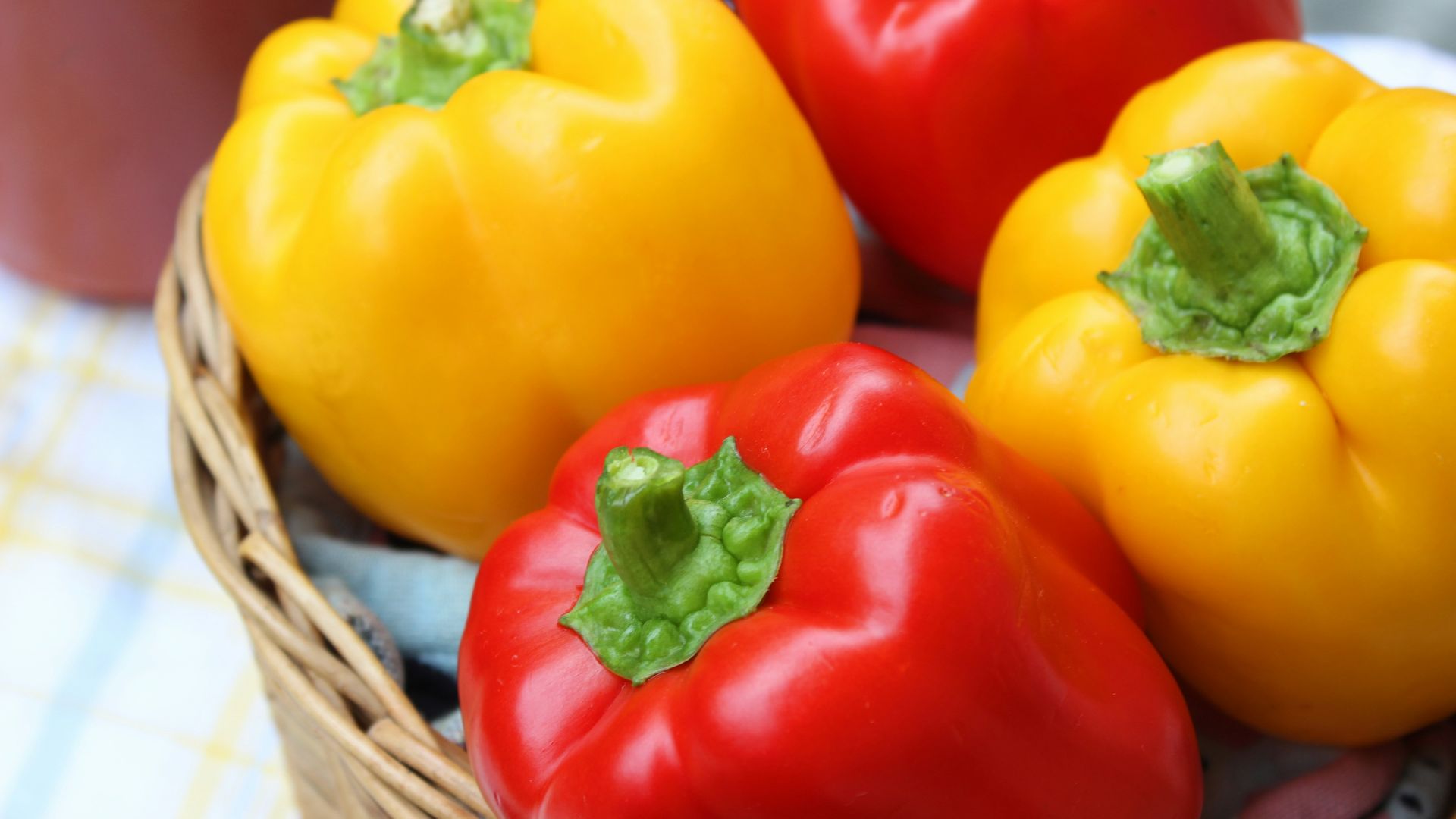 red and yellow bell peppers in brown woven basket