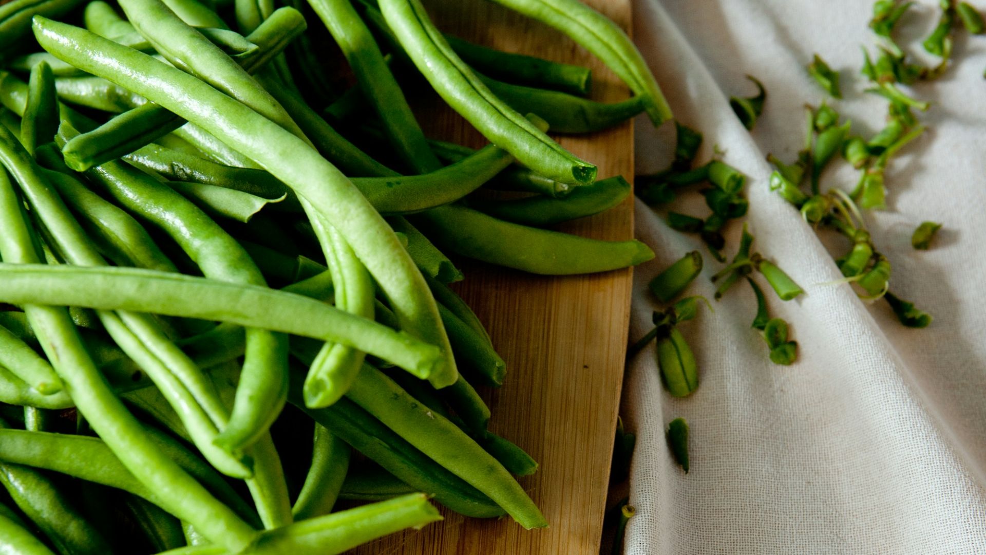 green peas on top of brown wooden chopping board