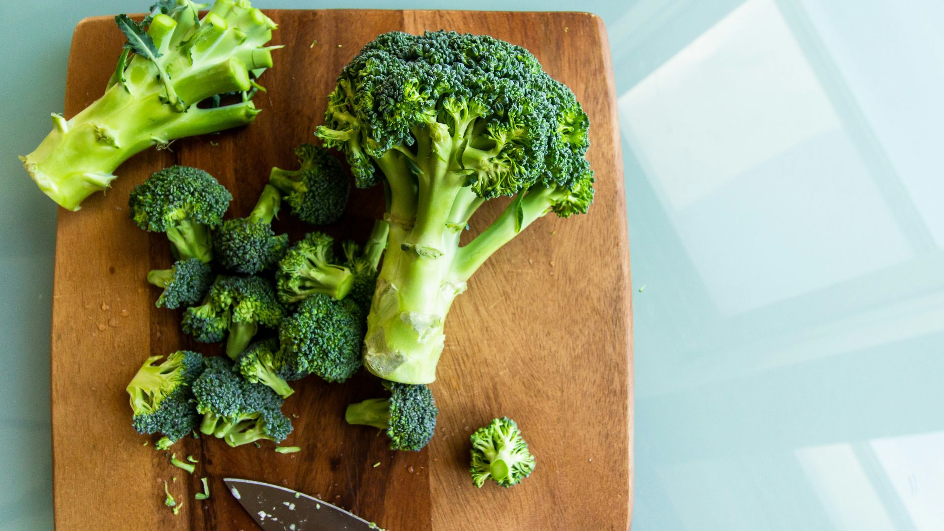 broccoli on brown wooden chopping board