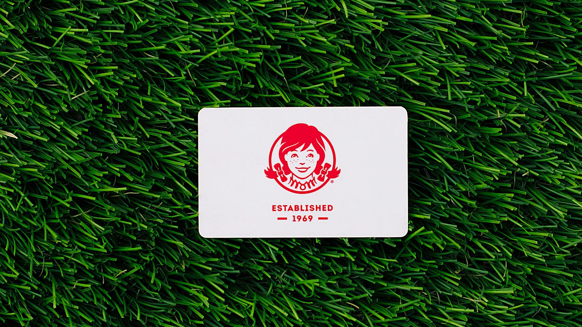 a white square sticker sitting on top of a lush green field