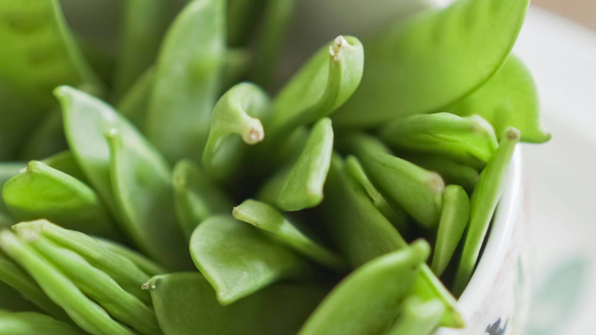 green beans on white and pink floral ceramic bowl
