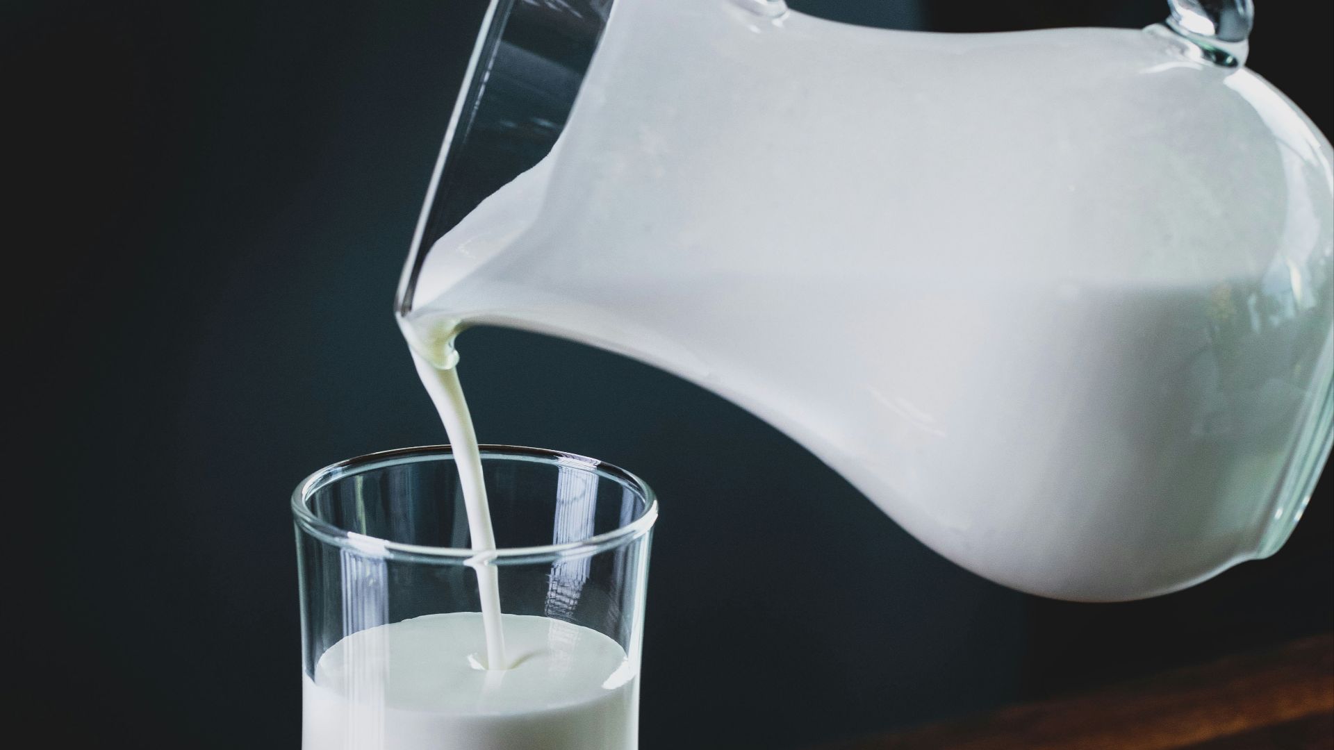 person pours milk into glass