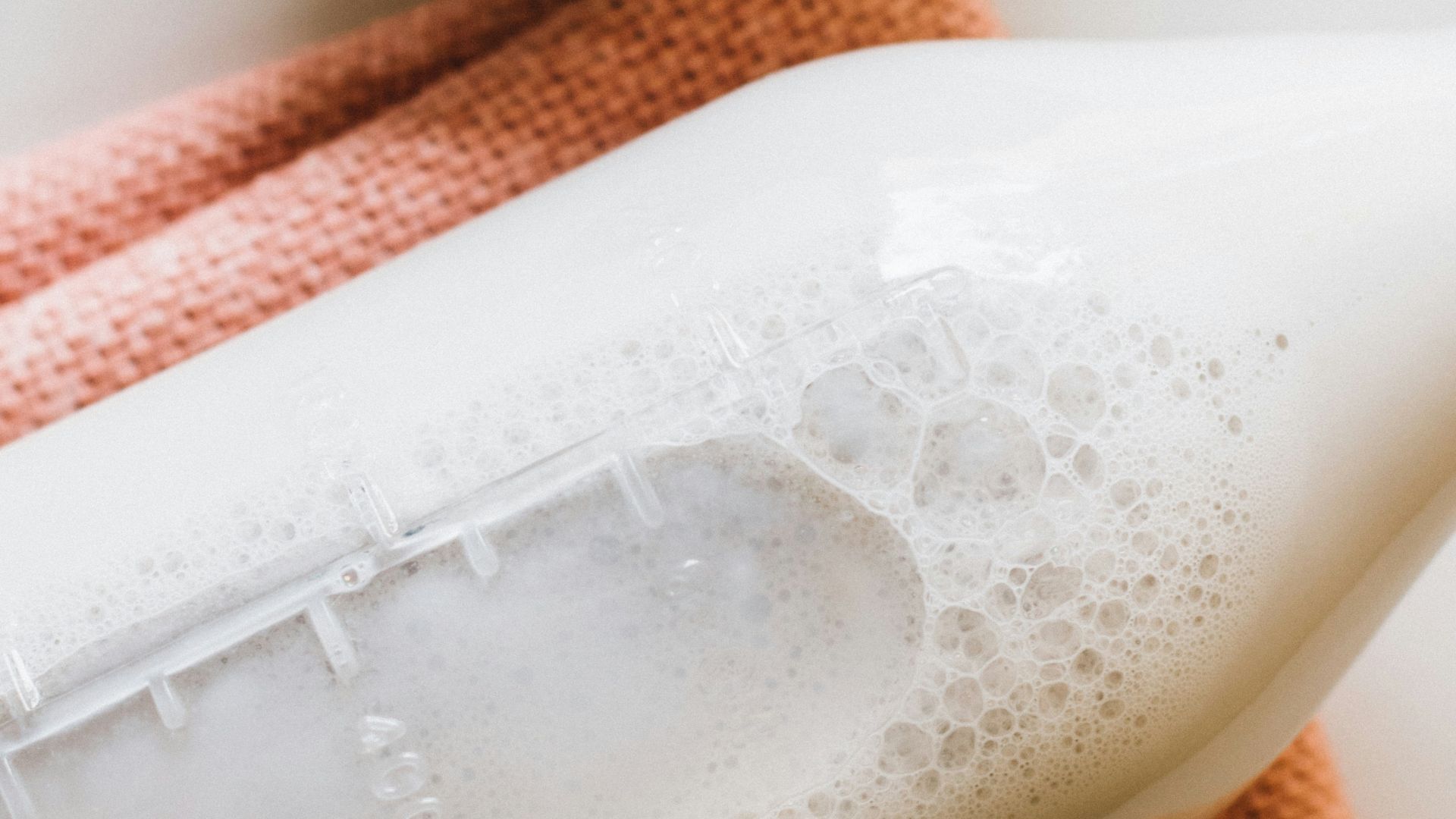closeup photo of milk bottle beside slice strawberries in white bowl