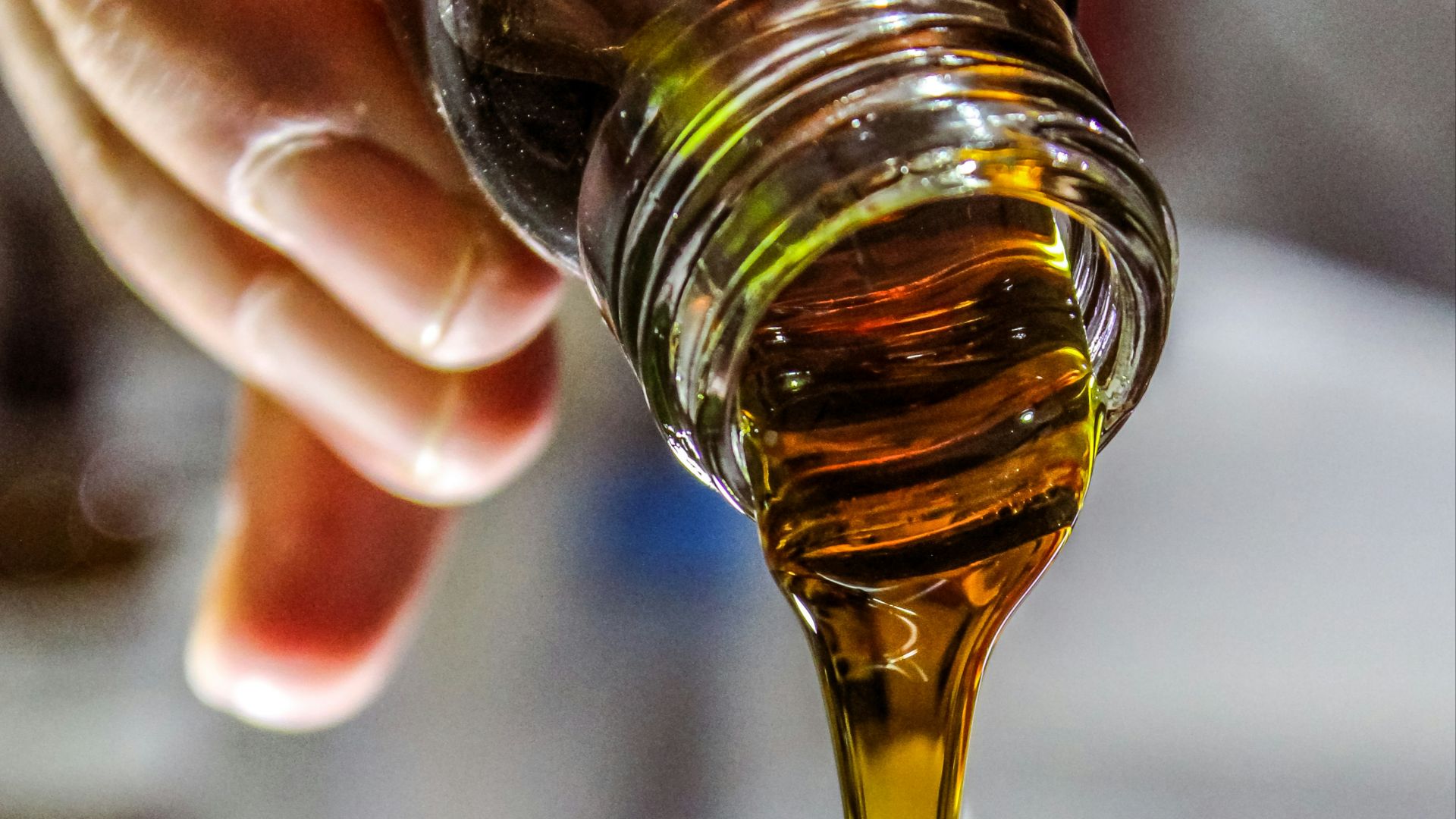 person holding clear drinking glass with brown liquid