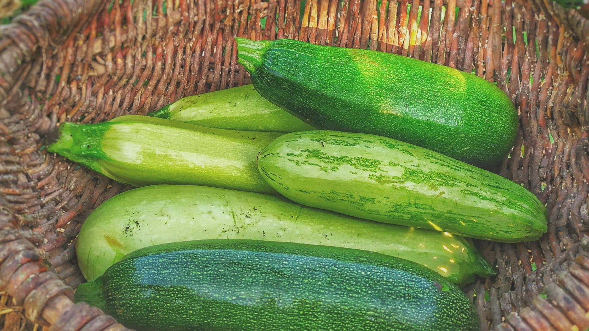 green cucumbers on round brown wicker basket