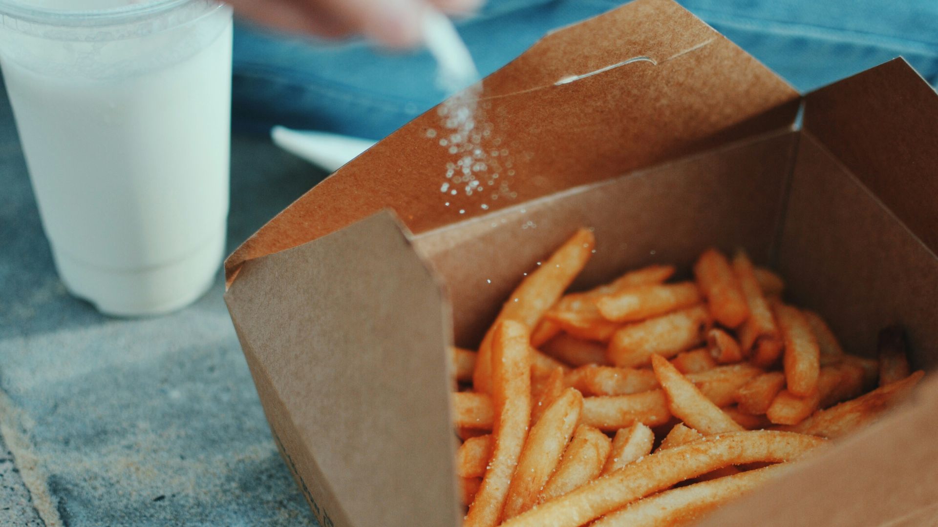 person sprinkling salt in fries