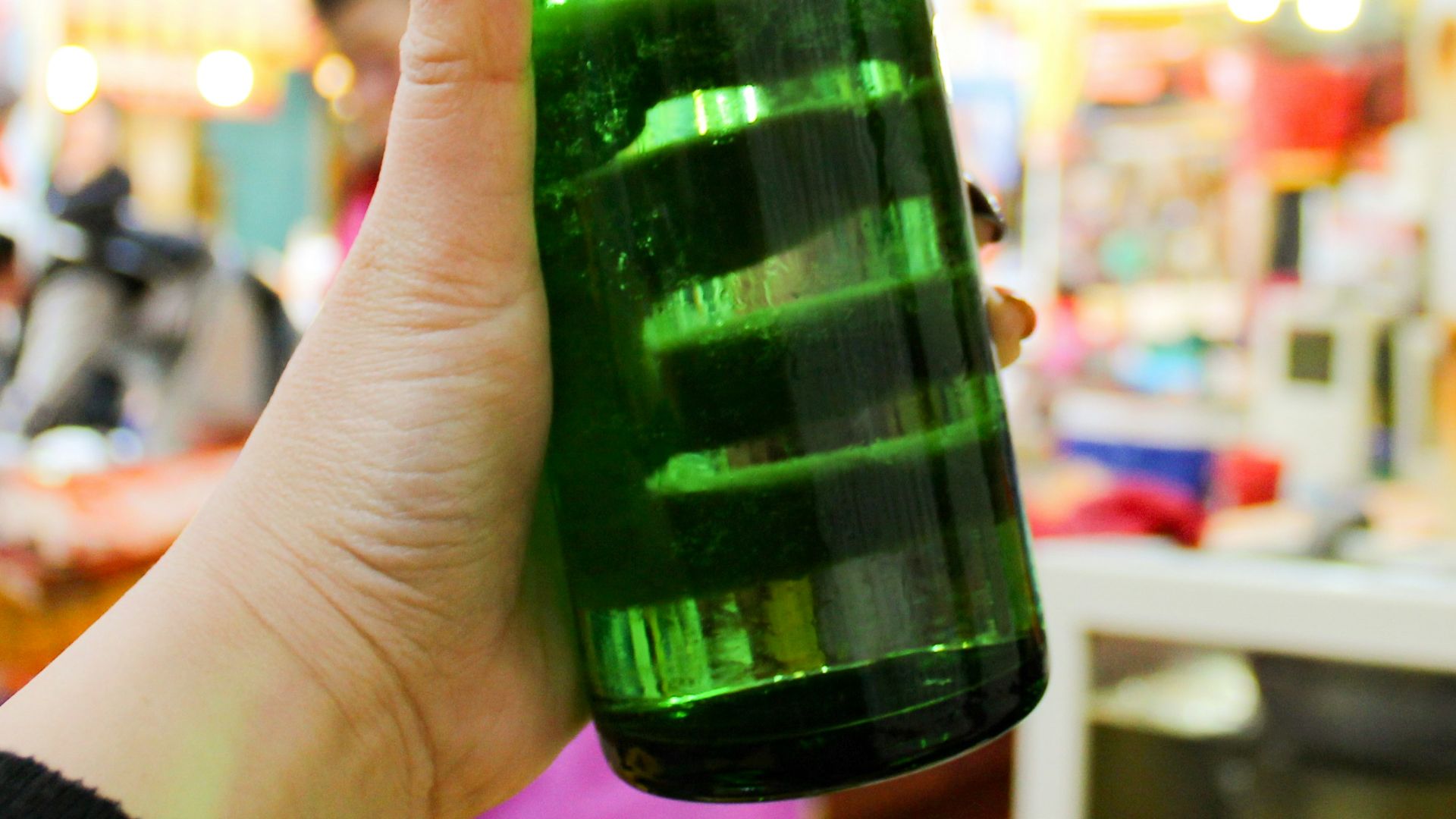 person holding green glass bottle