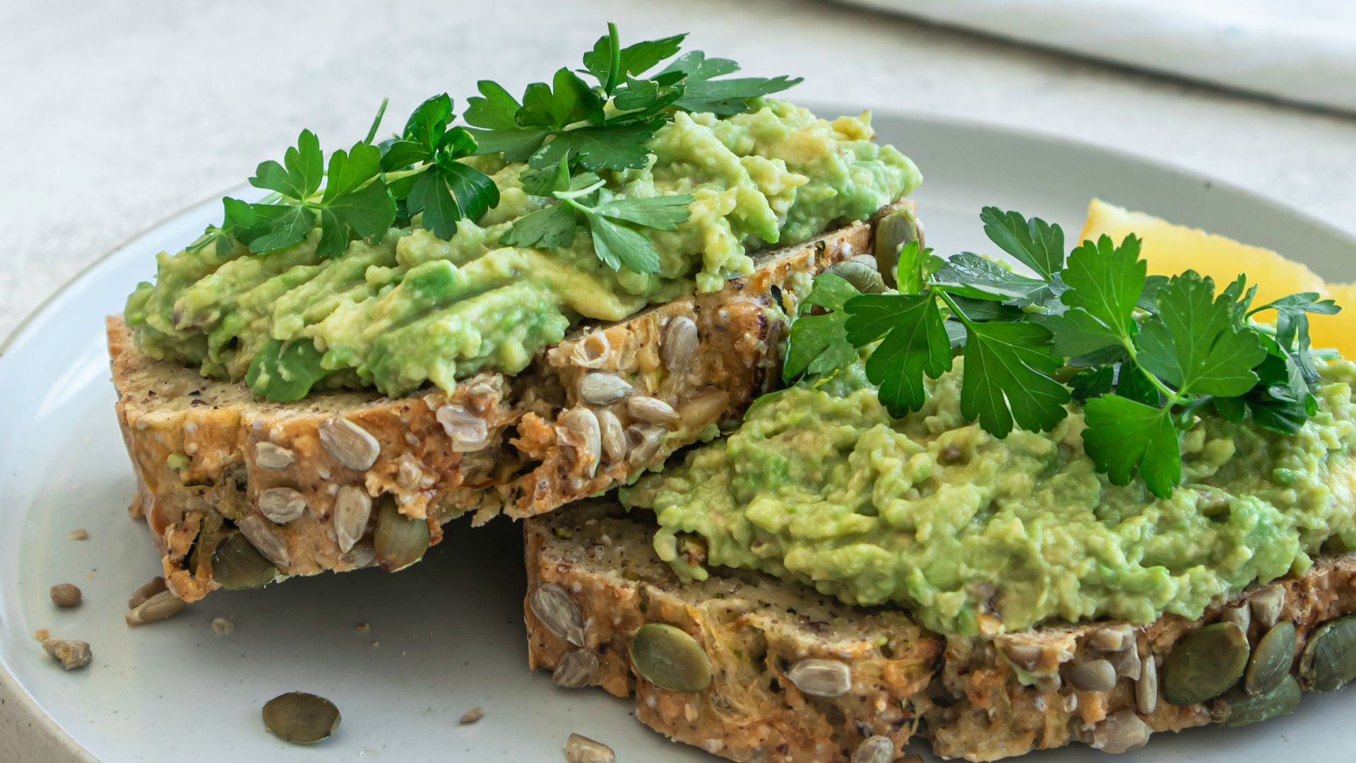 a white plate topped with a sandwich covered in guacamole