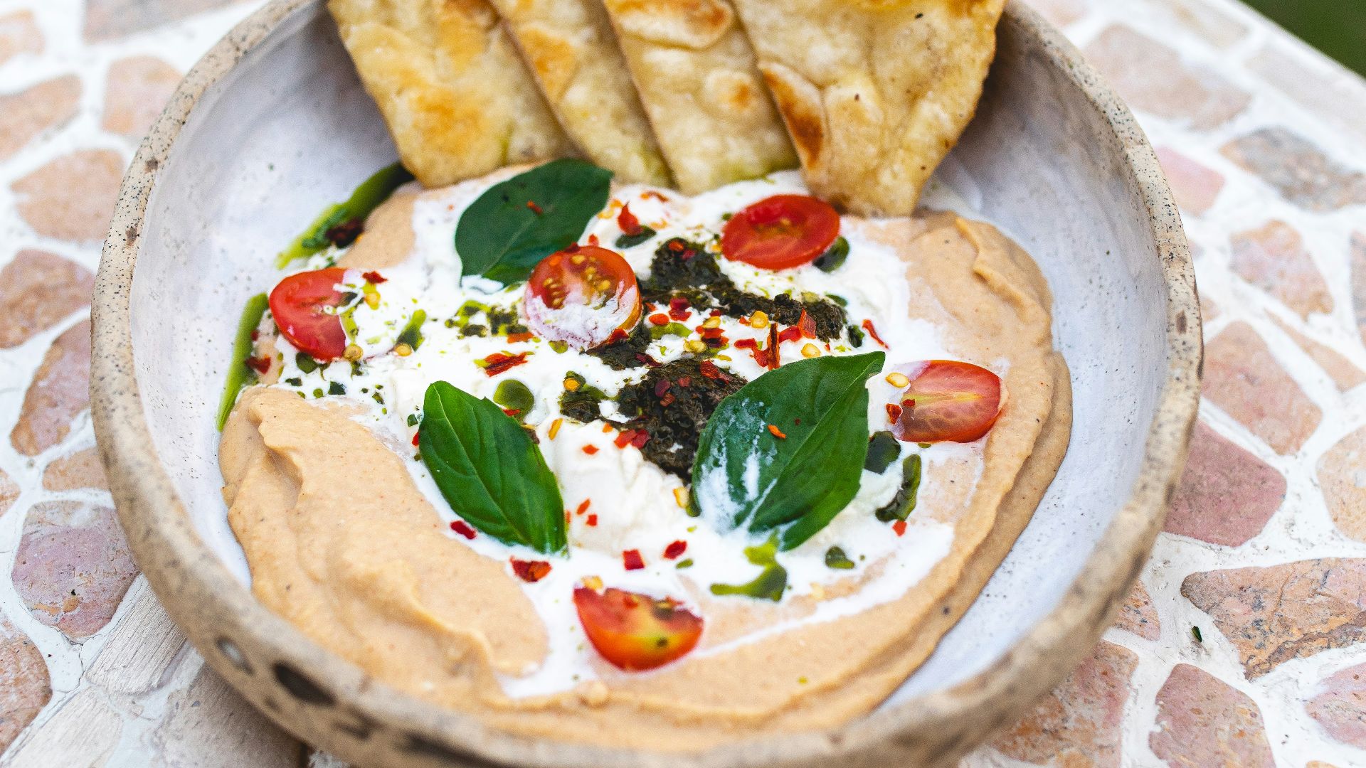 a bowl of hummus and pita chips on a table