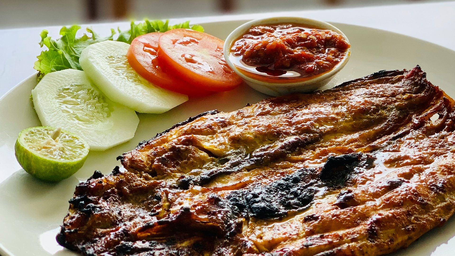 grilled meat with sliced cucumber and sliced cucumber on white ceramic plate