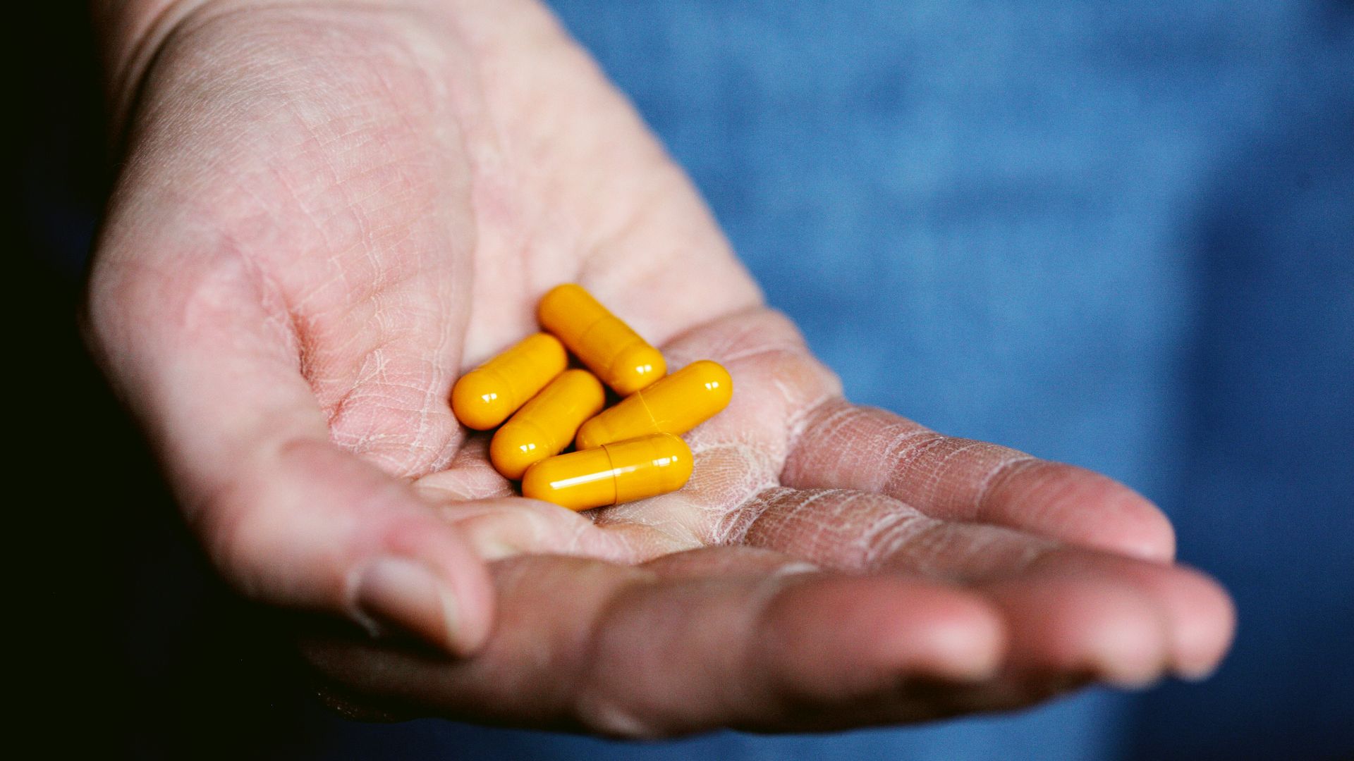 yellow medication pill on persons hand