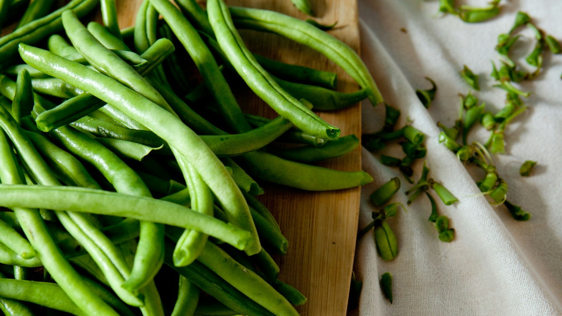green peas on top of brown wooden chopping board