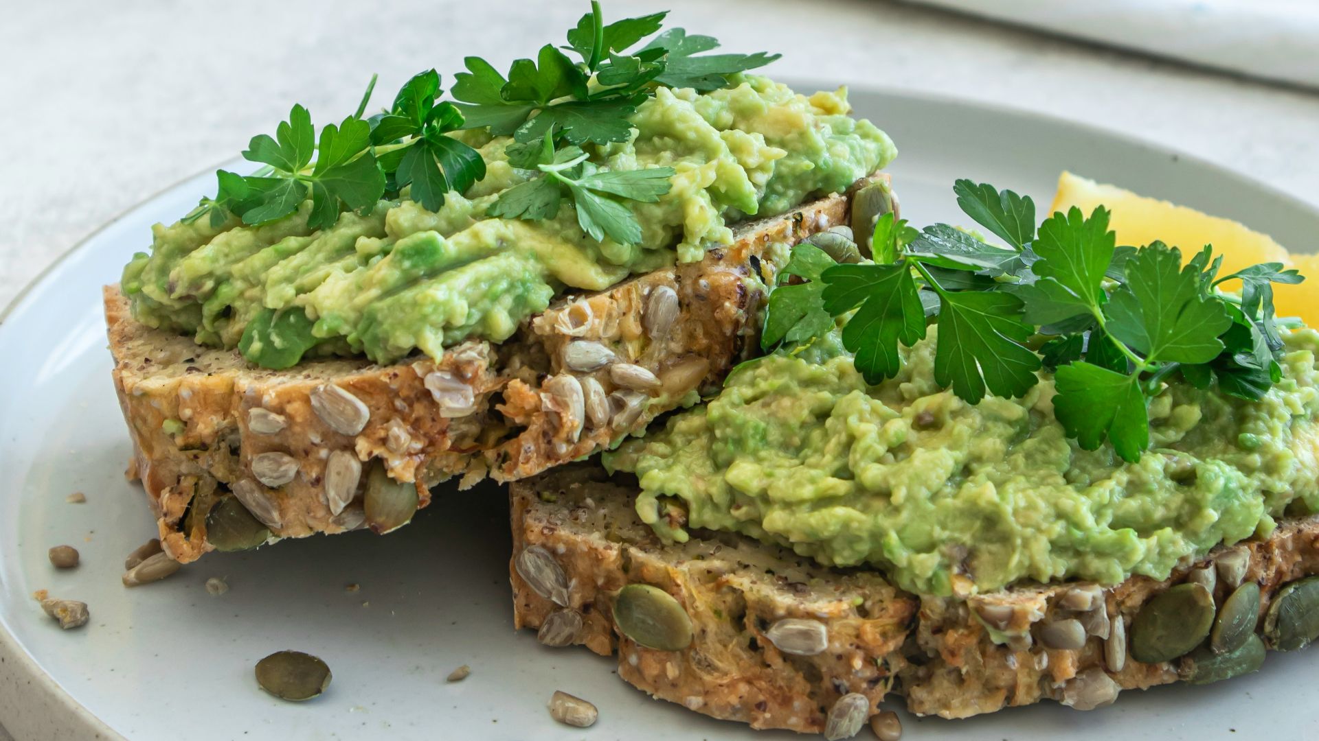 a white plate topped with a sandwich covered in guacamole