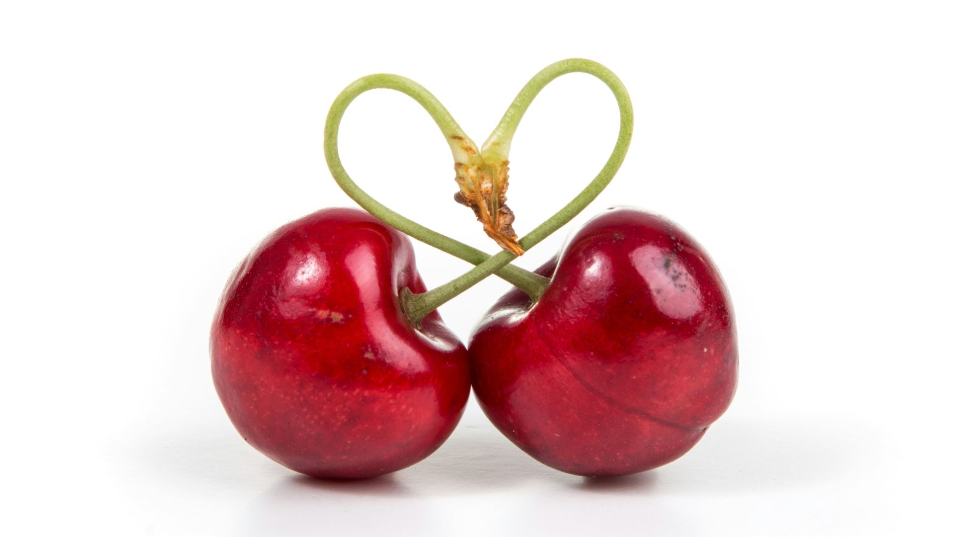 two red cherry fruits on white surface