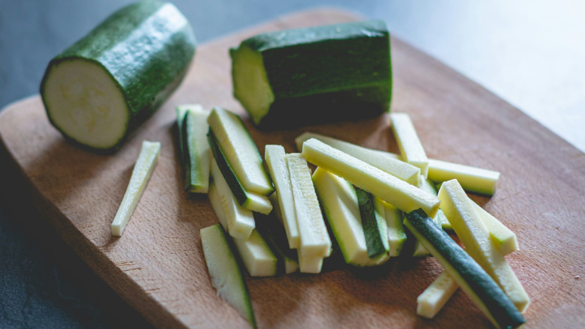 sliced green vegetable on brown wooden chopping board