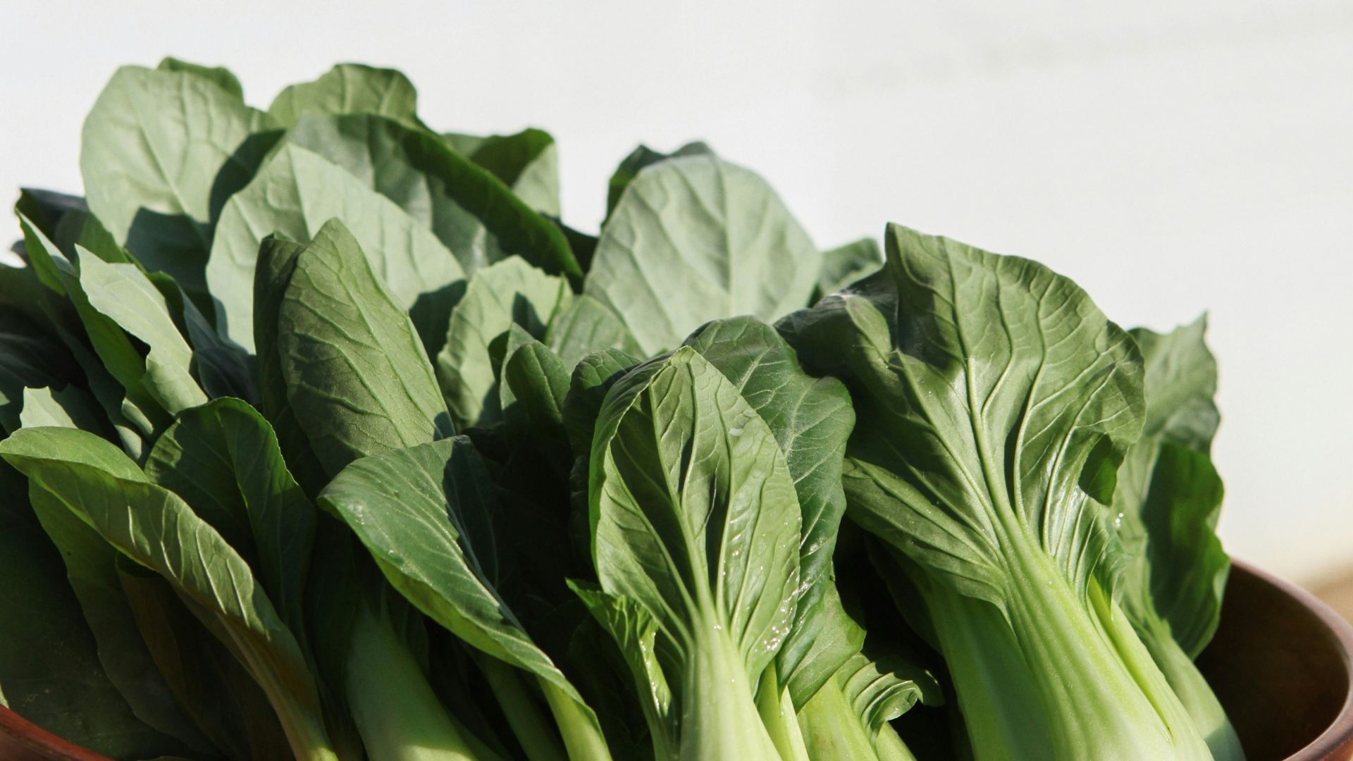 a wooden bowl filled with green leafy vegetables