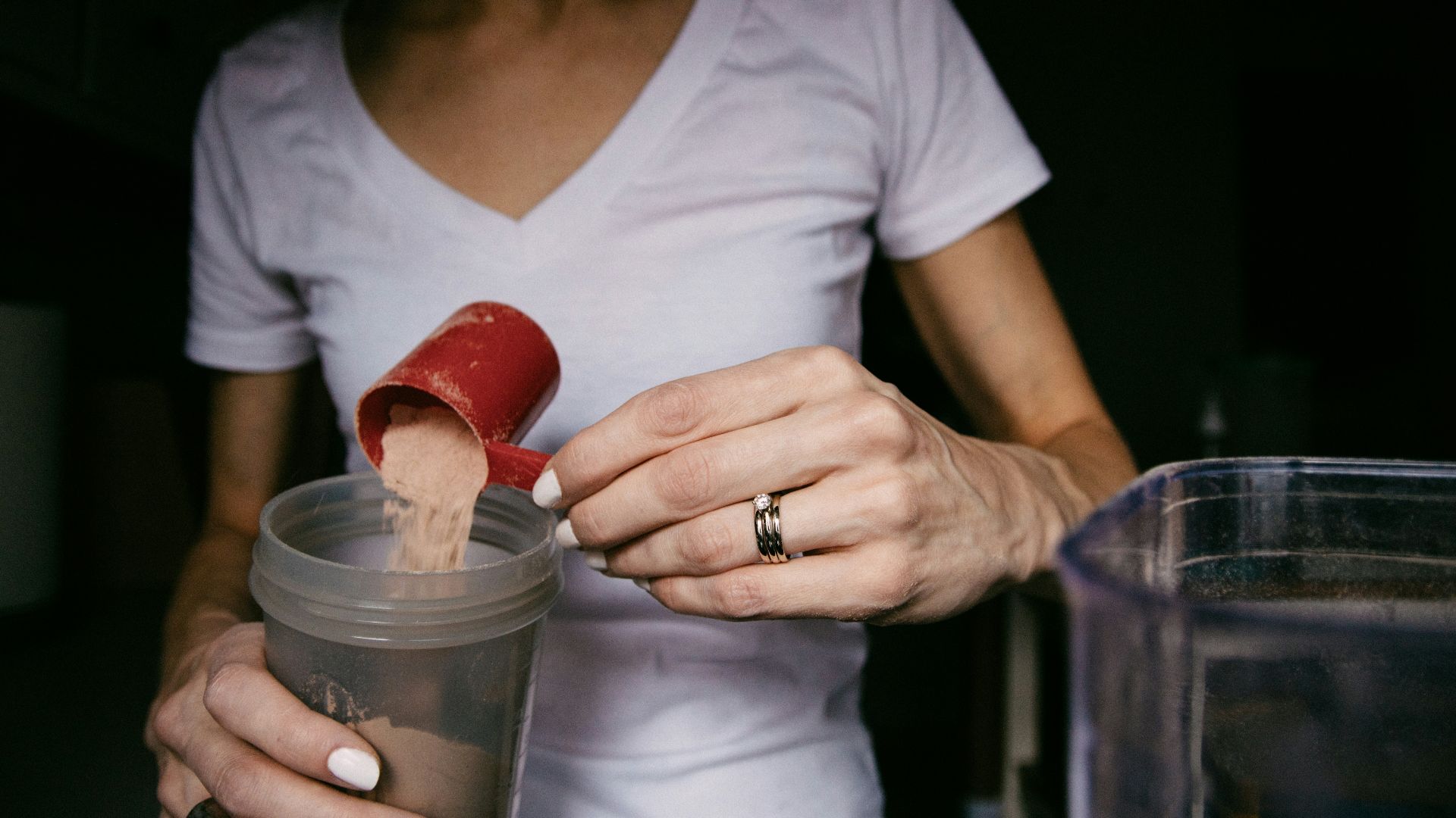 woman in white v neck shirt holding red heart shaped lollipop