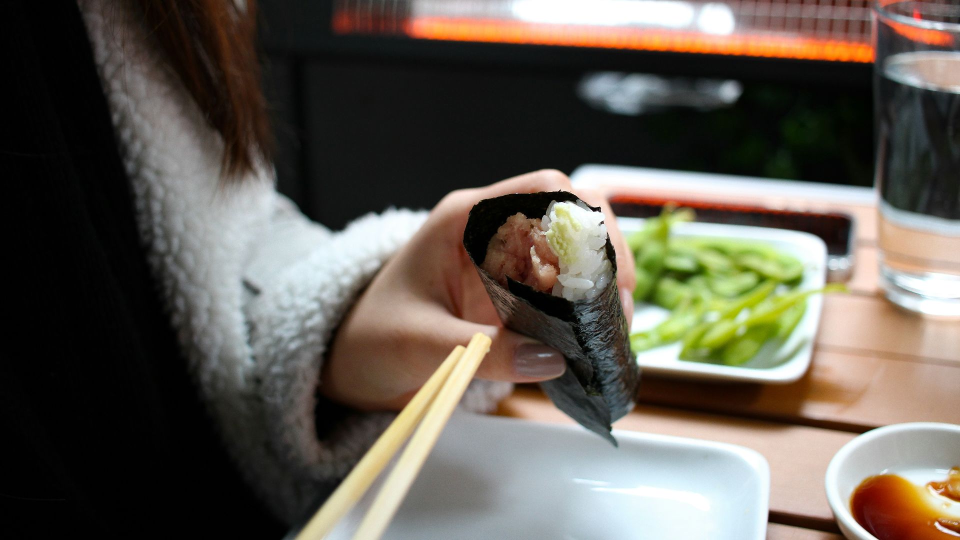 person holding a sushi in a white ceramic plate