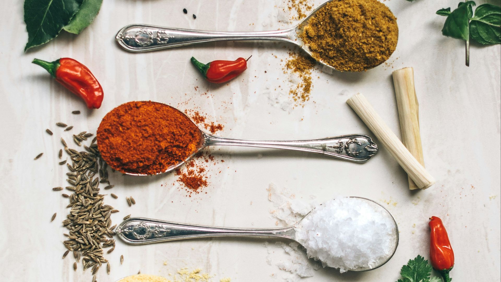 five gray spoons filled with assorted-color powders near chilli