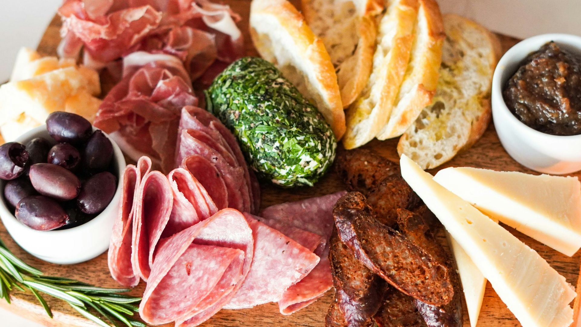 sliced meat with vegetable and bread on brown wooden chopping board