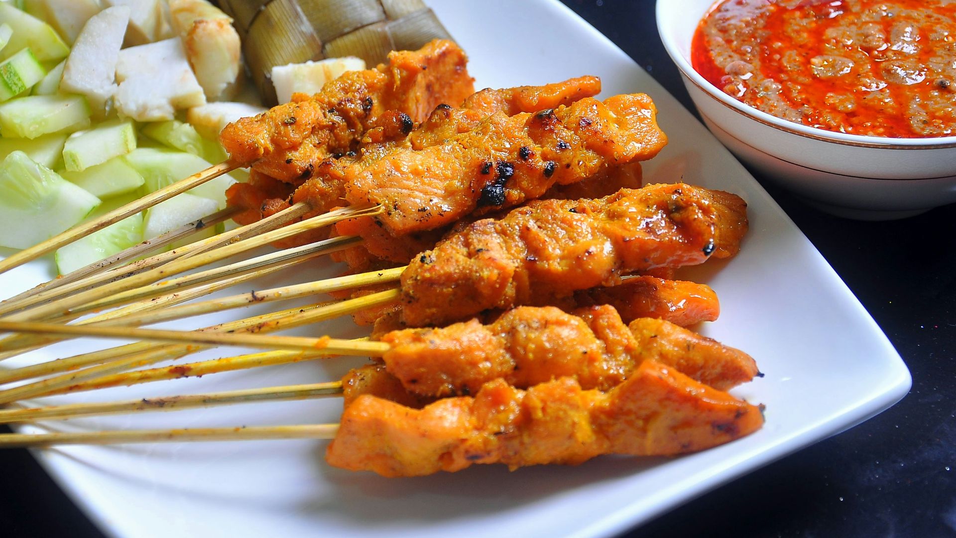 a white plate topped with meat and veggies next to a bowl of sauce