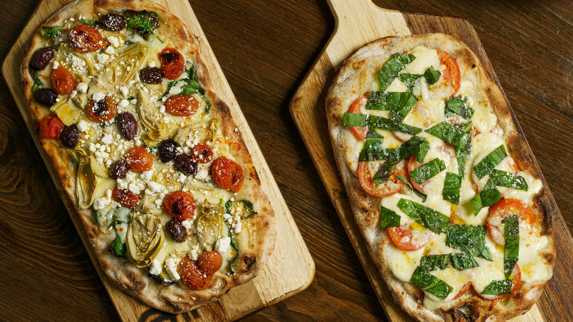 a couple of pizzas sitting on top of a wooden cutting board