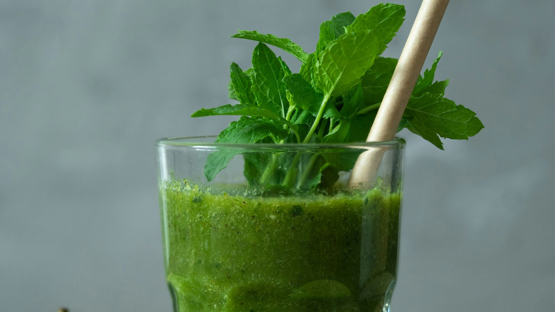 green liquid in clear drinking glass with straw