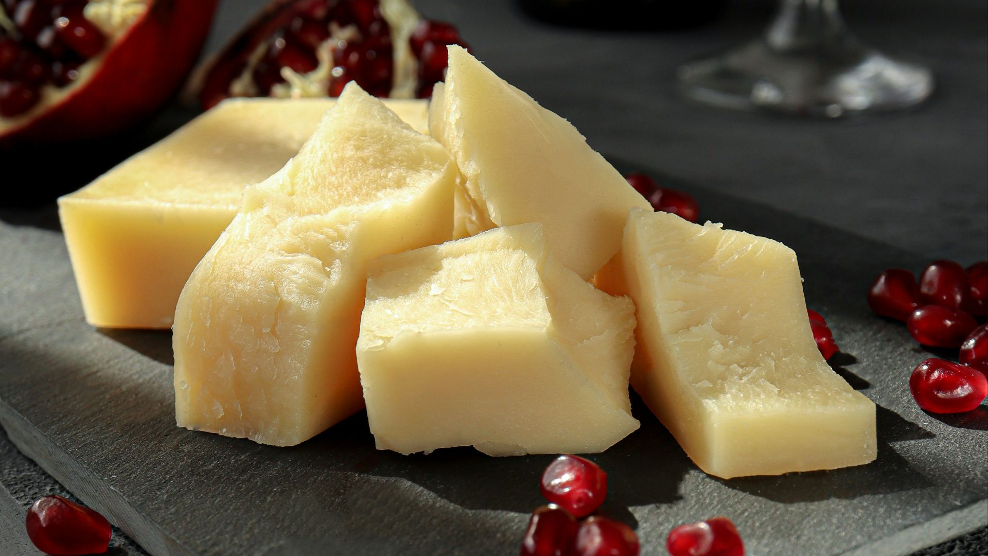 sliced cheese on black plate beside wine glass