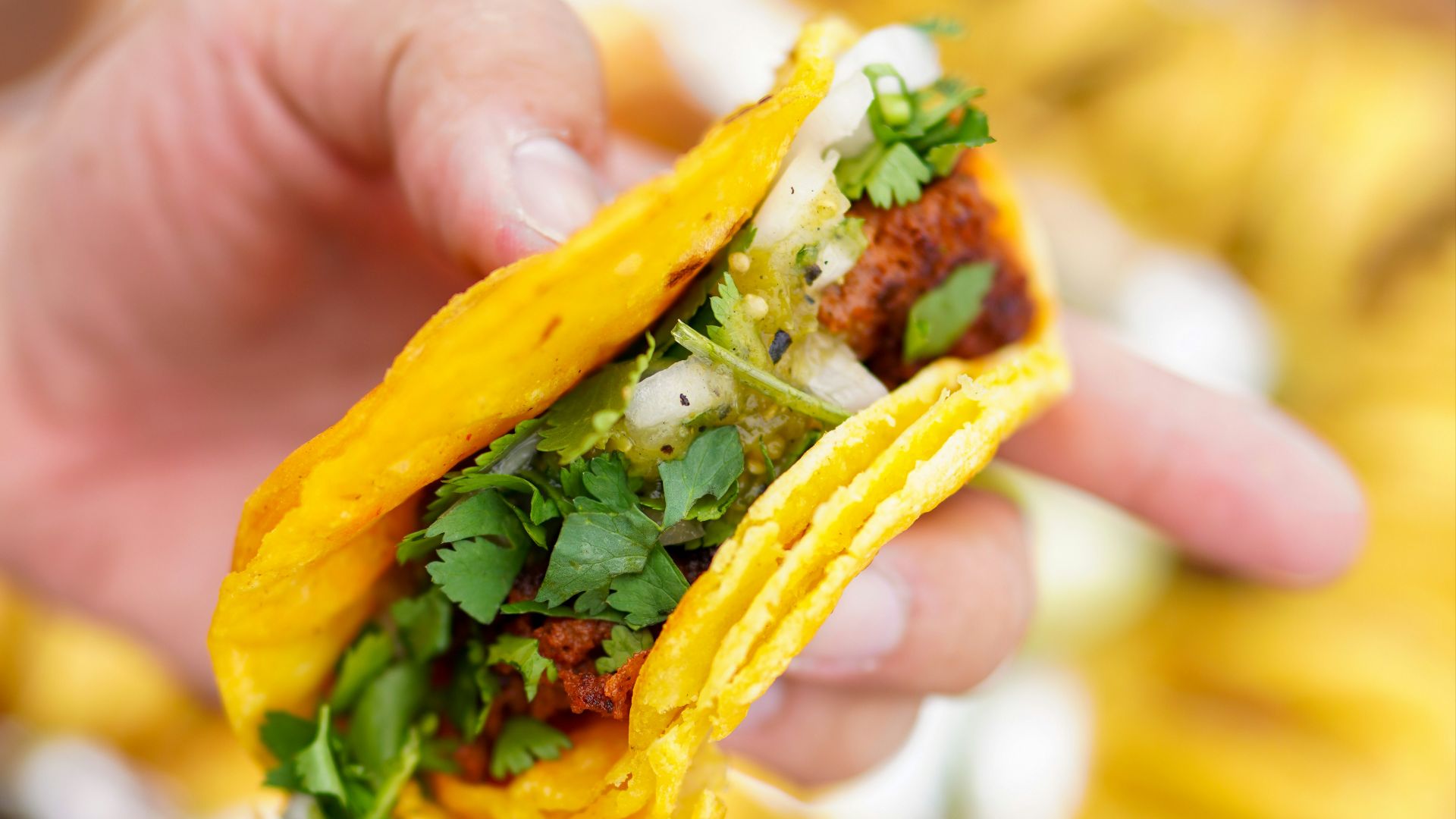 person holding a burger with green vegetable