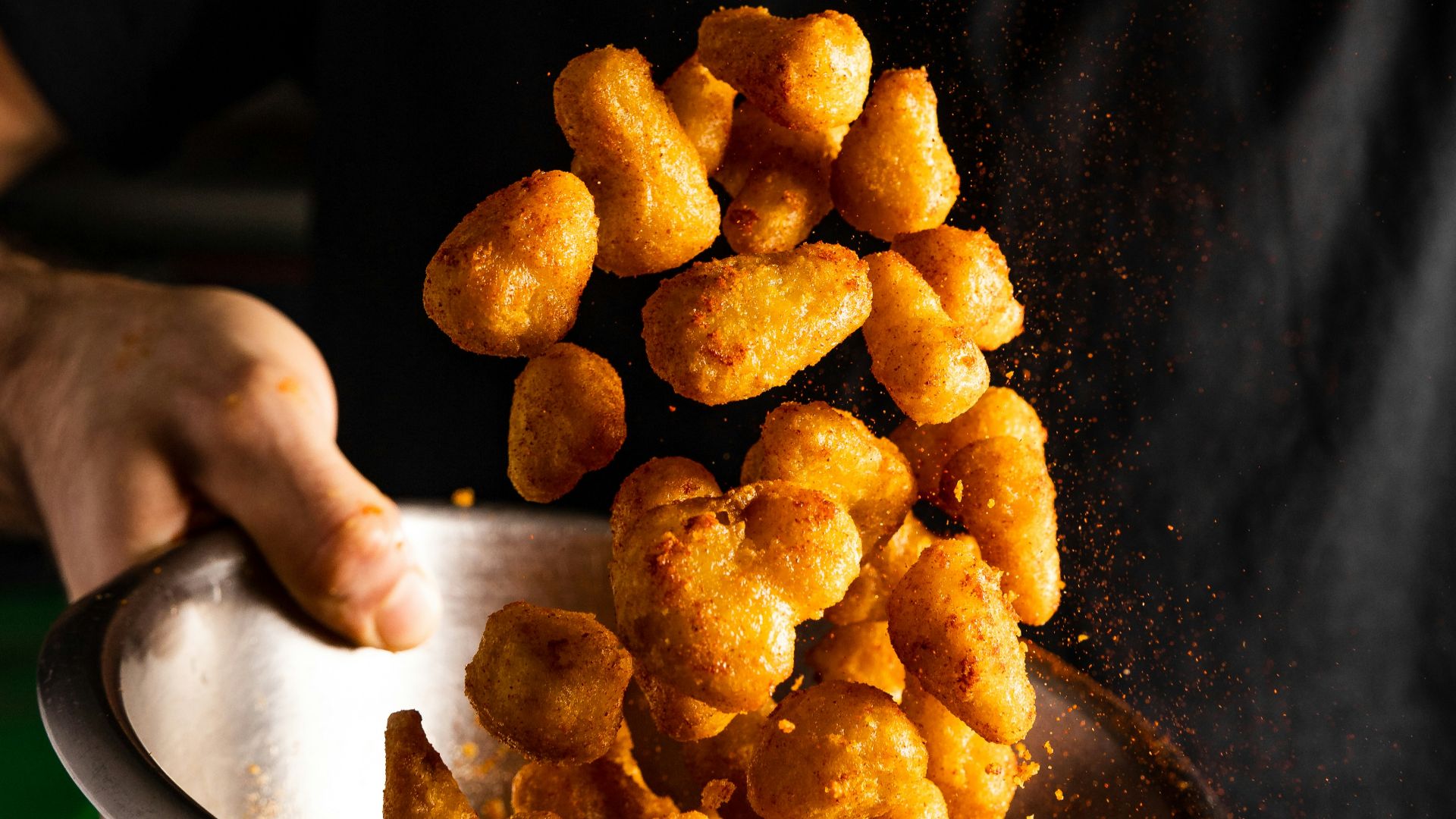 a person holding a bowl of fried food