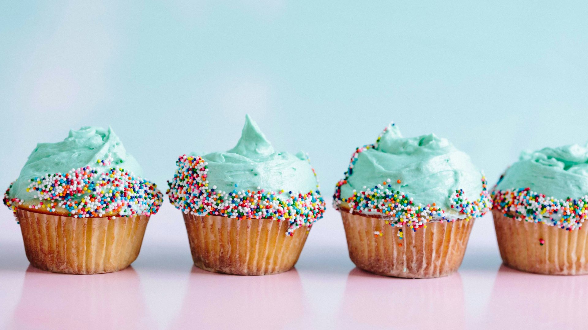 six teal icing cupcakes with sprinkles